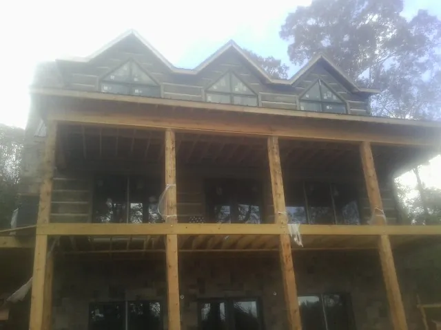 Dormers and porch framing on a large log home under construction — Roof Coating work by our crew in Olivet